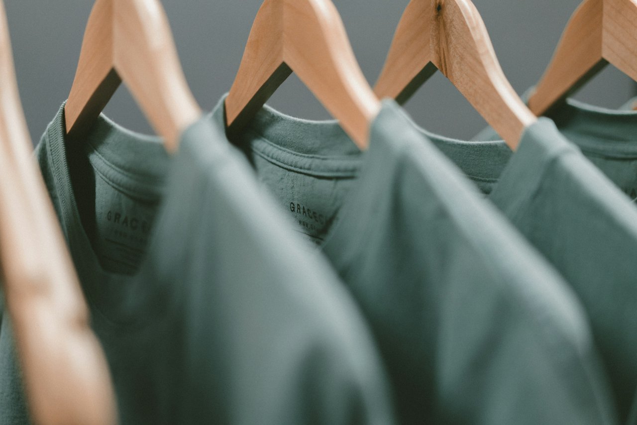 Green T-shirts hanging on wooden hangers